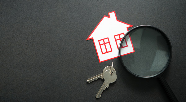 A house sticker beside keys and a magnifying lens